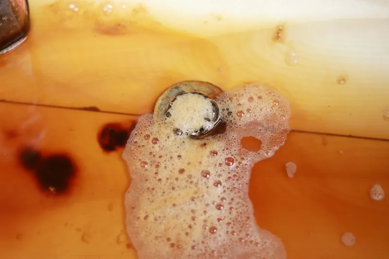 Agua sucia con espuma alrededor de un desagüe