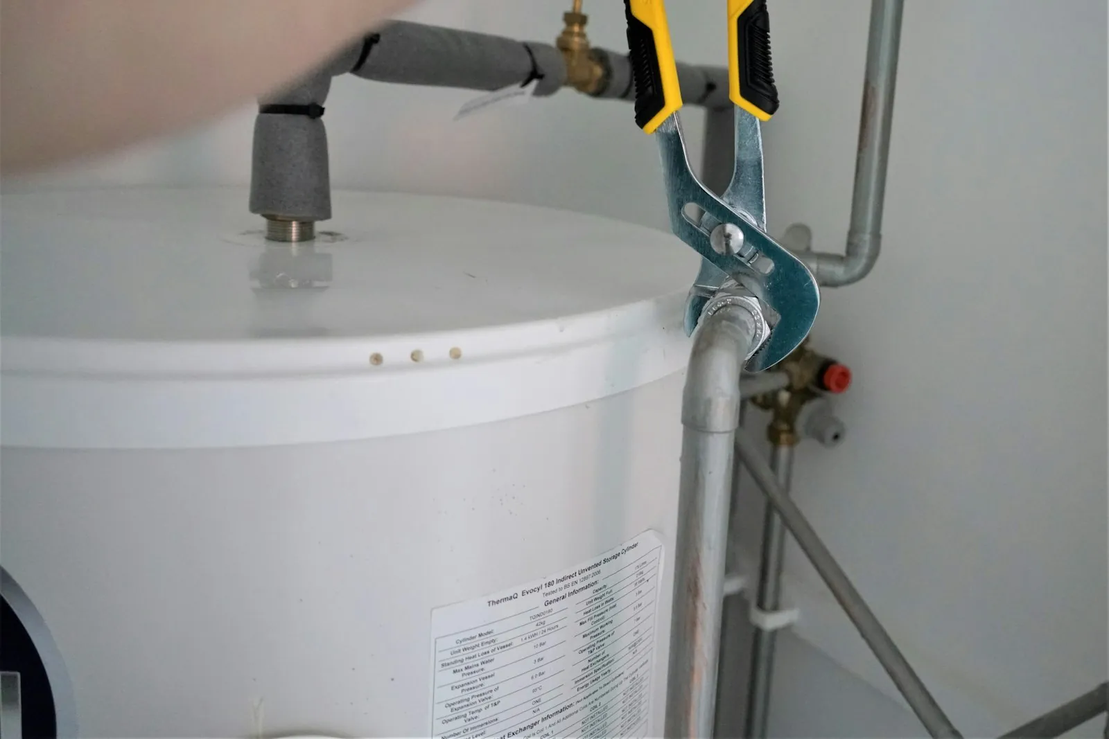 Técnico ajustando con una llave la conexión de un calentador de agua